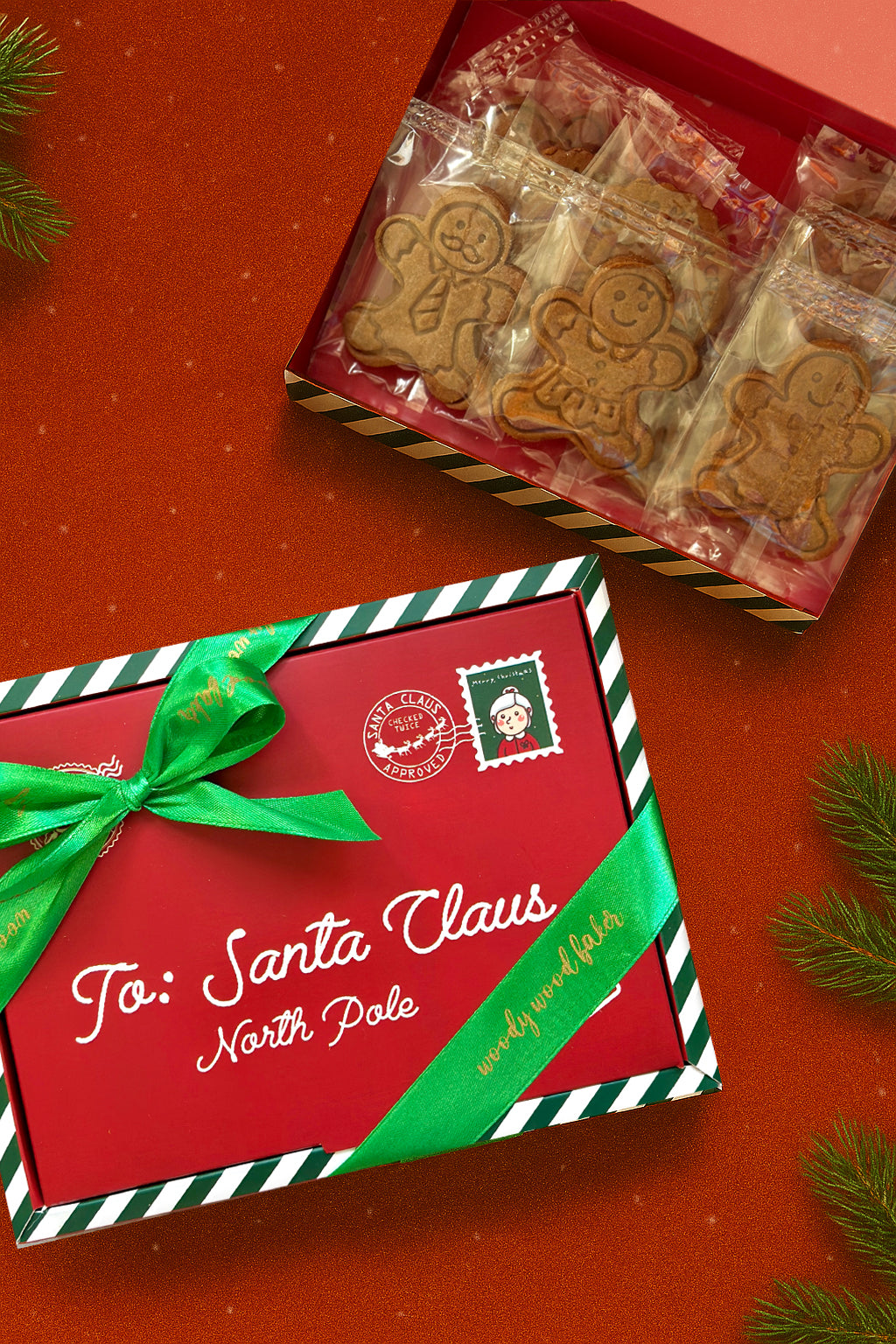 Red Christmas letterbox labelled ‘To: Santa Claus’ with green ribbon, filled with 12 individually wrapped Speculoos cookies. Festive nut-free cookie gift box by Woody Wood Baker.