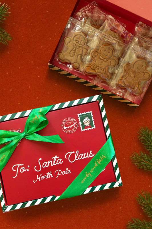 Red Christmas letterbox labelled ‘To: Santa Claus’ with green ribbon, filled with 12 individually wrapped Speculoos cookies. Festive nut-free cookie gift box by Woody Wood Baker.