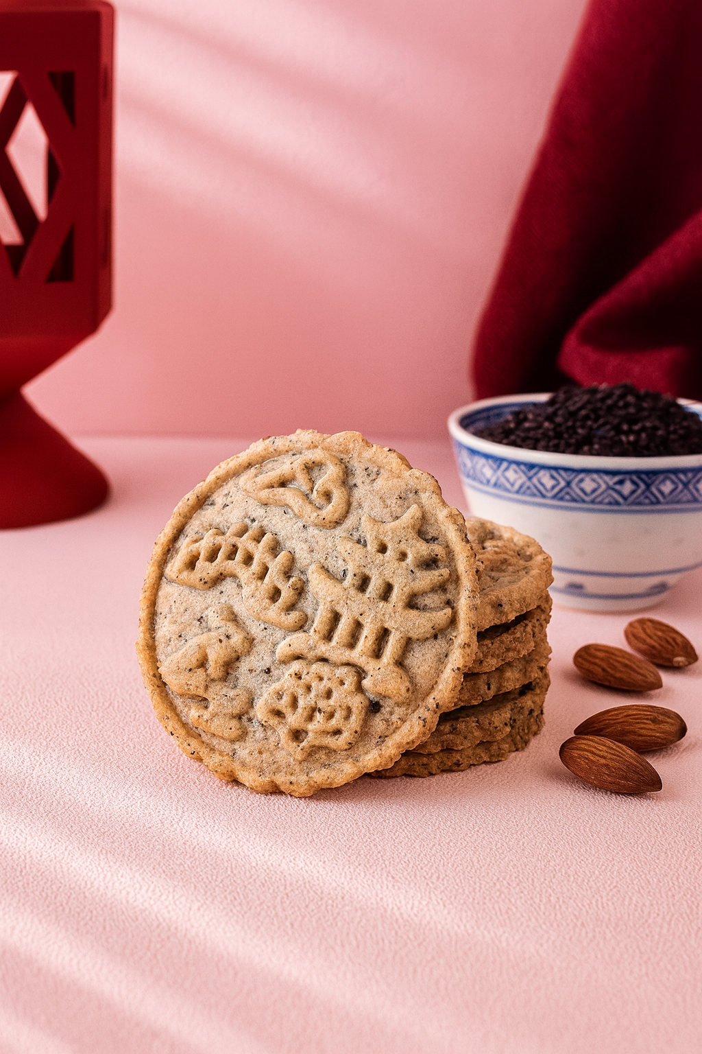 Black sesame Mooncookies – stack and loose cookies on pink surface with festive accents